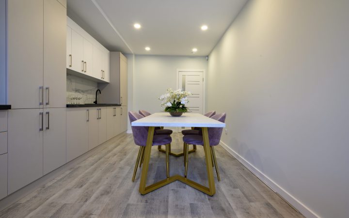 Interior of a large luxury beige and cream luxury kitchen with dining table, empty wall to the right
